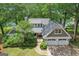 Stunning aerial view of a home with a sprawling lawn, mature trees, and a pristine lake at 3612 Bill Gardner Pkwy, Locust Grove, GA 30248