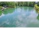 Aerial view showcasing a large lake with a fountain, surrounded by lush landscaping and a charming dock at 3612 Bill Gardner Pkwy, Locust Grove, GA 30248