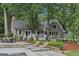 Inviting home features a stone patio, lounge chairs, and charming swing set amongst lush greenery and mature trees at 3612 Bill Gardner Pkwy, Locust Grove, GA 30248