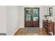 Inviting foyer with hardwood floors, a vintage wood dresser, and a view through glass paned front doors at 3612 Bill Gardner Pkwy, Locust Grove, GA 30248