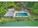 Aerial view of a private backyard pool with stone patio and lake access surrounded by mature landscaping at 3612 Bill Gardner Pkwy, Locust Grove, GA 30248