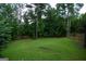 Serene backyard features mature trees, a well-maintained lawn, and a wooden fence for privacy and shade at 12043 Olmstead Dr, Fayetteville, GA 30215