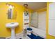 Bright yellow bathroom with a pedestal sink, toilet, shower and tub combo, offering a functional and clean space at 12043 Olmstead Dr, Fayetteville, GA 30215