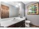 Neutral bathroom featuring a vanity, toilet, wood-trimmed window, and decorative globe light at 6230 S Summers Cir, Douglasville, GA 30135