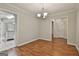 Dining area with hardwood floors, chandelier, and neutral walls, with a view of the kitchen and hallway at 107 Jennings Yard, Peachtree City, GA 30269