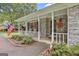 Inviting front porch with classic white columns, red hanging baskets and brick accents, showcasing southern charm at 107 Jennings Yard, Peachtree City, GA 30269