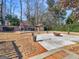 Landscaped backyard with a brick fireplace, dining set, firepit and patio spaces, surrounded by trees at 200 Magnolia Ct, Mcdonough, GA 30252