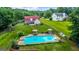 Aerial view of backyard with an in-ground pool, patio with umbrellas and a playground surrounded by trees at 161 Mills Dr, Covington, GA 30016