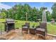 Outdoor patio area with a grill, comfortable seating, and a beautiful view of the landscaped backyard and surrounding trees at 161 Mills Dr, Covington, GA 30016