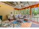 Charming screened porch featuring wicker furniture, floral cushions, ceiling fan and string lights overlooking the backyard at 161 Mills Dr, Covington, GA 30016