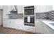 Well-equipped kitchen with stainless steel double oven, gas cooktop, white cabinets and mosaic backsplash at 1993 Reynolds Sw Dr, Atlanta, GA 30315