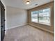 Bedroom featuring a neutral carpet, large window letting in natural light, and a dark wooden door at 473 Cherry Creek Dr, Loganville, GA 30052