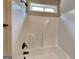 Shower tub with a white surround, bronze fixtures, and a small window for natural light at 473 Cherry Creek Dr, Loganville, GA 30052