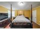 Bedroom with yellow walls featuring a large, dark wood four-poster bed and bright natural light at 295 Pinehurst Dr, Stockbridge, GA 30281