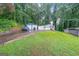 View of property with multiple garages, parking spaces, and a grassy yard with mature trees at 295 Pinehurst Dr, Stockbridge, GA 30281