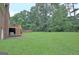Lush backyard showing the home's rear exterior, a brick wall and wooded trees at 550 Hawthorne Dr, Fayetteville, GA 30214