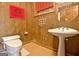 Bathroom featuring a toilet and a pedestal sink, complemented by warm wood paneling and vintage decor at 550 Hawthorne Dr, Fayetteville, GA 30214