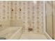 Bathroom featuring classic wallpaper, tiled floors, and marble-lined bathtub with glass shower door at 550 Hawthorne Dr, Fayetteville, GA 30214