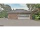 Detached brick garage with a white door set against a backdrop of lush green trees and a gravel driveway at 550 Hawthorne Dr, Fayetteville, GA 30214