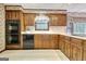 Well-lit kitchen featuring wooden cabinets, black appliances, and a window with a lovely view at 550 Hawthorne Dr, Fayetteville, GA 30214