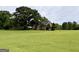 Expansive backyard view with lush lawn, mature trees, and home with covered patio at 10 Wigwam Cir, Whitesburg, GA 30185