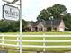 Charming home with a 'Lake Wampum' sign, white fence, and lush greenery at 10 Wigwam Cir, Whitesburg, GA 30185