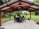 Covered outdoor patio featuring ceiling fans, dining table set, and views of the lush backyard at 10 Wigwam Cir, Whitesburg, GA 30185