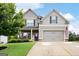 Charming two-story home featuring a well-manicured lawn, gray siding, brick accents and an attached two-car garage at 372 Cobblestone Trl, Dallas, GA 30157