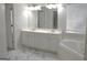 Bathroom featuring white cabinets, dual sinks, and a large soaking tub with marble flooring at 3700 Newhalem Sw St, Atlanta, GA 30331