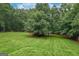 A large backyard is enhanced by mature trees and lush lawn at 4080 Derby Dr, Cumming, GA 30040