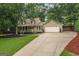View of a lovely two-story home with a two-car garage and a long driveway with mature trees at 4080 Derby Dr, Cumming, GA 30040