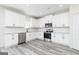 Modern kitchen featuring stainless steel appliances, granite countertops, white cabinets, and gray wood-look flooring at 3392 Arabian Farm Ln, Dacula, GA 30019