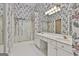 Well-lit bathroom with double vanity, floral wallpaper, and glass-enclosed shower at 133 Sea Island Dr, Peachtree City, GA 30269