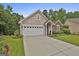 Charming home exterior with a two-car garage, arched entryway, and well-manicured landscaping at 133 Sea Island Dr, Peachtree City, GA 30269