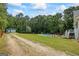 Wide view of the backyard with pool, shed, grassy area, and wooden fence and gravel driveway at 150 Surrey Chase Dr, Social Circle, GA 30025