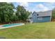 Aerial view of a backyard with an in-ground pool, grassy area, and home with white deck and stairs at 150 Surrey Chase Dr, Social Circle, GA 30025