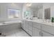 Bright bathroom features double sink vanity, a soaking tub, and a frameless shower at 150 Surrey Chase Dr, Social Circle, GA 30025