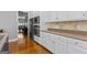 Modern kitchen with stainless steel appliances, white cabinets, hardwood floors, light countertops, and modern backsplash at 150 Surrey Chase Dr, Social Circle, GA 30025