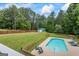 Aerial view of a backyard pool with grass lawn and a storage shed with a wooden fence in the background at 150 Surrey Chase Dr, Social Circle, GA 30025