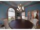 Elegant dining room with blue walls, wood trim, a chandelier, and a round table with upholstered chairs at 715 Branchview Ct, Mcdonough, GA 30252
