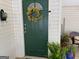 Green front door with decorative wreath, potted plants, and door bell at 1470 Dunn Rd, Cumming, GA 30040
