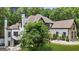 Side view of luxurious home featuring white exterior, gray roof, and stone accents, framed by lush greenery at 2878 Heather Row Sw Rdg, Lilburn, GA 30047
