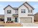 Two-story brick home boasts a covered front porch, attached garage, and well-manicured lawn at 445 Sawmill Trce, Hampton, GA 30228