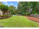 Well-maintained backyard with lush green lawn, mature trees, and a sparkling pool in the background at 134 Mellington Ln, Peachtree City, GA 30269