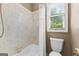 Tiled bathroom with a shower-tub combination, and a toilet next to a window at 134 Mellington Ln, Peachtree City, GA 30269