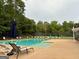 Community pool and seating area with lounge chairs, umbrellas, and a view of the tennis court at 1129 River Green Ct, Mcdonough, GA 30252