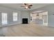 Bright living room with a fireplace, ceiling fan, neutral walls, and wood-look flooring, next to kitchen at 221 Ruthe Cv, Locust Grove, GA 30248