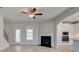 Bright living room with a fireplace, ceiling fan, neutral walls, and wood-look flooring, next to kitchen at 221 Ruthe Cv, Locust Grove, GA 30248