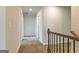 Bright hallway with neutral walls, plush carpeting, and dark railing, offering a welcoming transition between spaces at 506 Alford Cv # 89, Fairburn, GA 30213