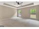 Large bedroom with neutral carpet, tray ceiling, and abundant natural light at 240 Turnbridge Cir, Peachtree City, GA 30269